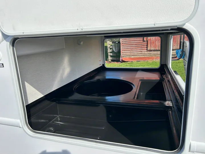 RV rental outdoor kitchen: View inside a clean, open exterior compartment with a black sink and counter setup.. Thor Motor Coach Chateau 2026