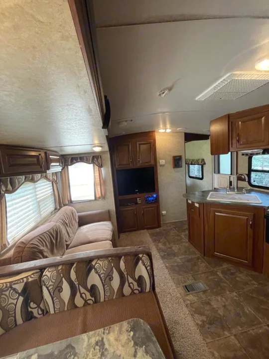 RV rental interior features a comfortable living area with sofa, kitchen with sink, and entertainment center.. Keystone RV Cougar 2012