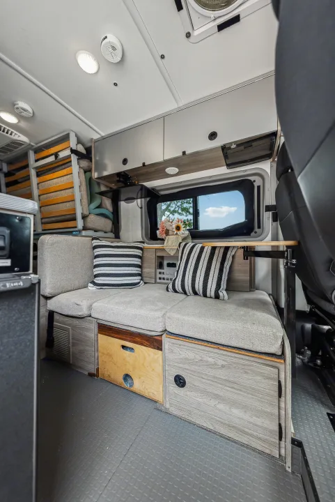 Cozy RV rental interior with bench seating, pillows, window view, and ample storage, perfect for mobile living.. Winnebago Solis Pocket 2022