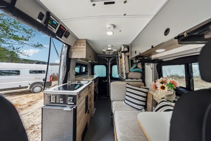 This RV rental showcases a modern camper van interior: kitchen with sink, comfy seating, overhead storage, and scenic outdoor views.. Winnebago Solis Pocket 2022