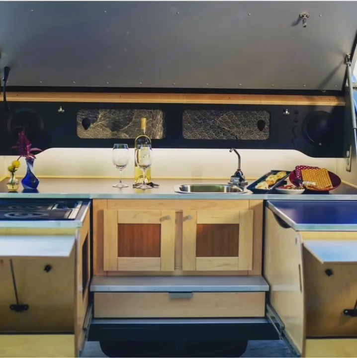 RV rental kitchen: a sleek outdoor setup with a stove, sink, wine, and snacks. Perfect for glamping adventures.. Pin Drop Travel Trailers Scout 2022