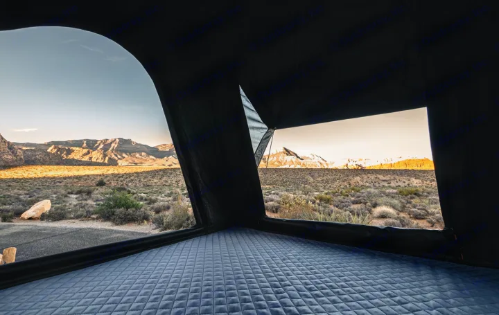 Comfortable RV rental view: quilted bed inside tent with scenic desert mountains at sunrise.. Toyota Other 2025