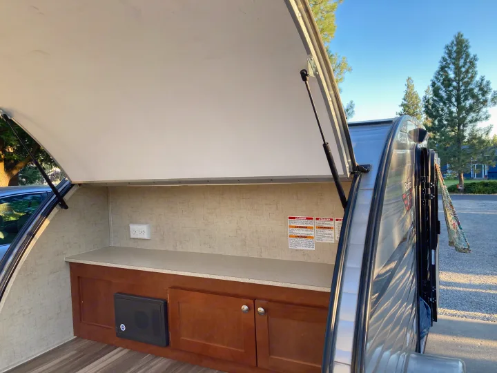 Inside an RV rental's open outdoor kitchen, featuring a counter, cabinets, and power outlet, perfect for camping.. Riverside RV Retro 2017