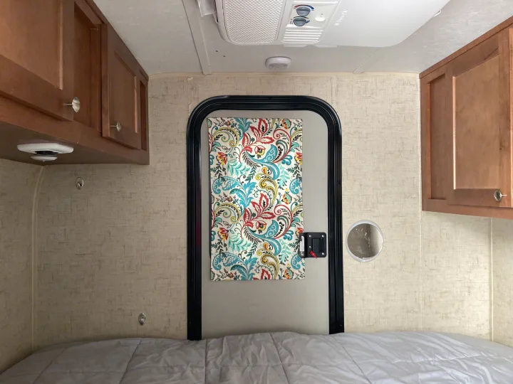 RV rental interior: cozy sleeping area with bed, wood cabinets, and AC.. Riverside RV Retro 2017
