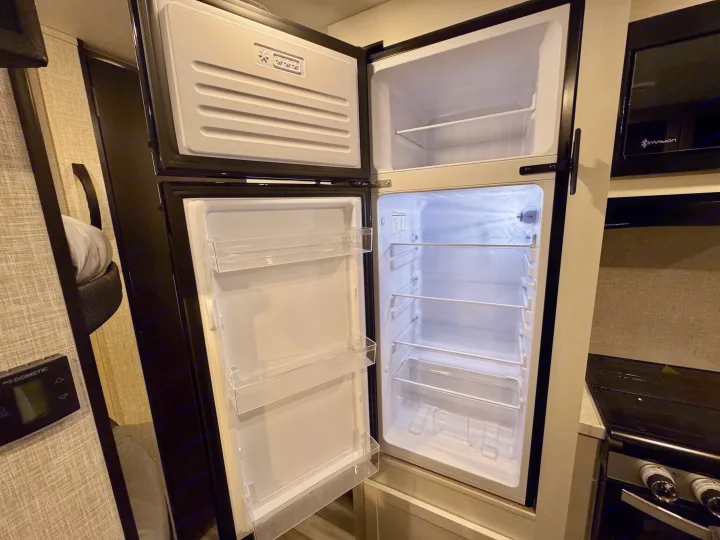 RV rental kitchen appliances: empty, clean fridge/freezer with open doors, ready for use.. Jayco 260BH 2025