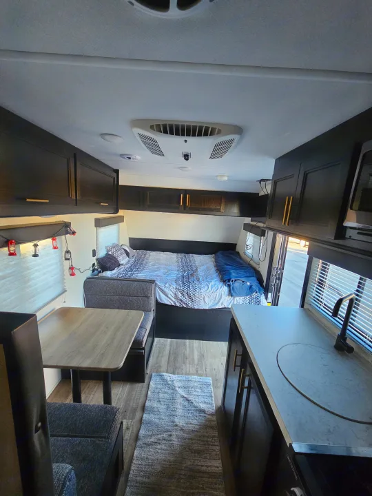 Inside an RV rental, showcasing the comfortable bed, dinette, and functional kitchen space.. Forest River Cherokee Wolf Pup 2022