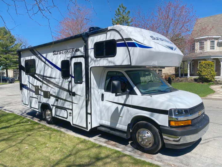 White Sunseeker Class C RV rental parked on a residential street under a clear blue sky.. Forest River Sunseeker LE 2021