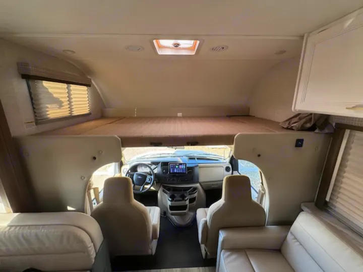 Interior of an RV rental featuring a large cab-over bunk, driver's cockpit, and living area seating.. Thor Eddie Bauer 28EB 2025