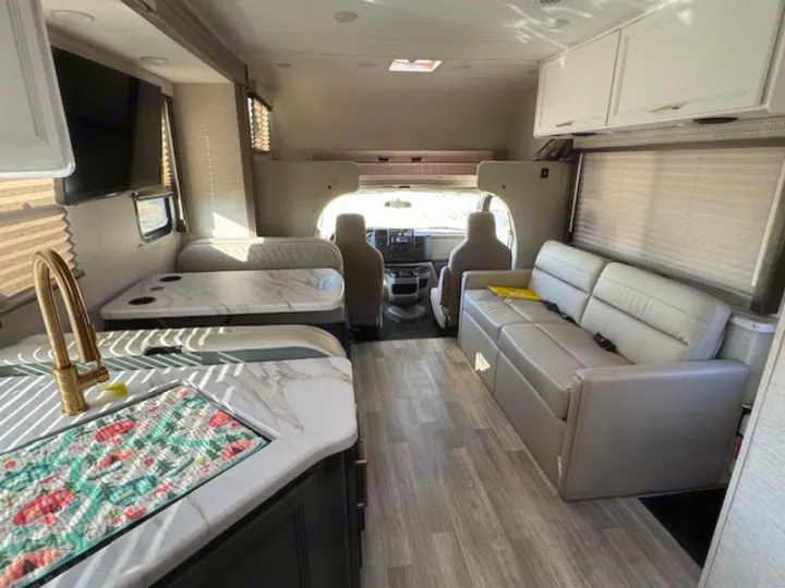 Inside an RV rental: full view of the living area, including kitchen, dinette, sofa, and cockpit.. Thor Eddie Bauer 28EB 2025