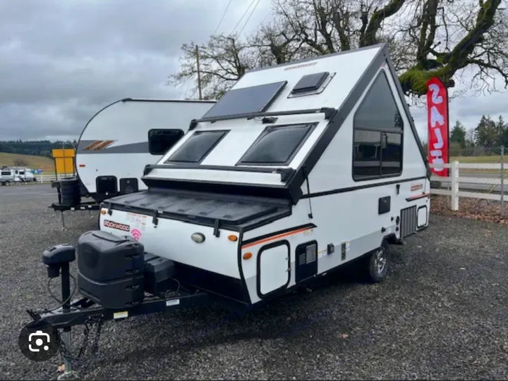 White A-frame travel trailer RV for rent. This compact camping unit features solar panels & large windows.. Forest River Rockwood LTD 2023