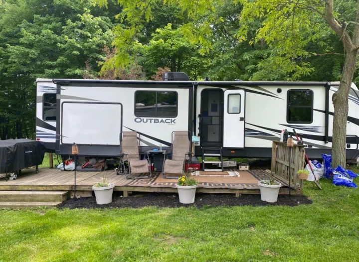 Enjoy this Outback travel trailer RV rental, featuring a deck with chairs, set in a peaceful, treed campground.. Keystone RV Outback 2019