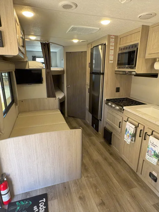 Spacious RV rental interior featuring a convertible dinette, bunk beds, and a fully equipped kitchen.. Coachmen Coachmen Catalina Summit 2025