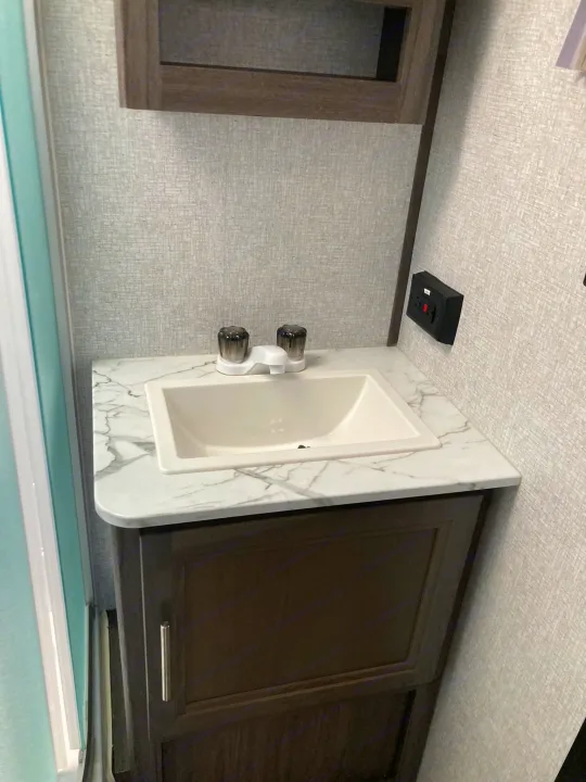 Inside this RV rental: a modern, compact bathroom vanity with a clean sink, marble-look counter, and cabinet storage.. Dutchmen Kodiak Ultimate 2020