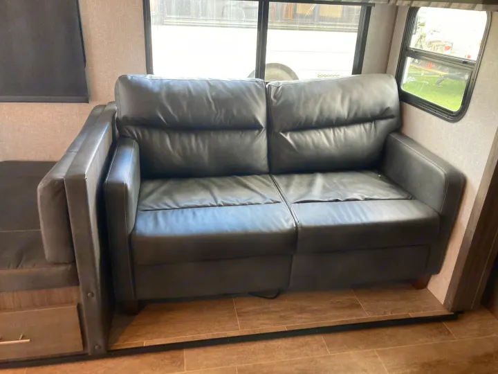 Comfortable dark grey RV sofa and dinette seating inside an RV rental. Ideal living space for road trips.. Dutchmen Kodiak Ultimate 2020