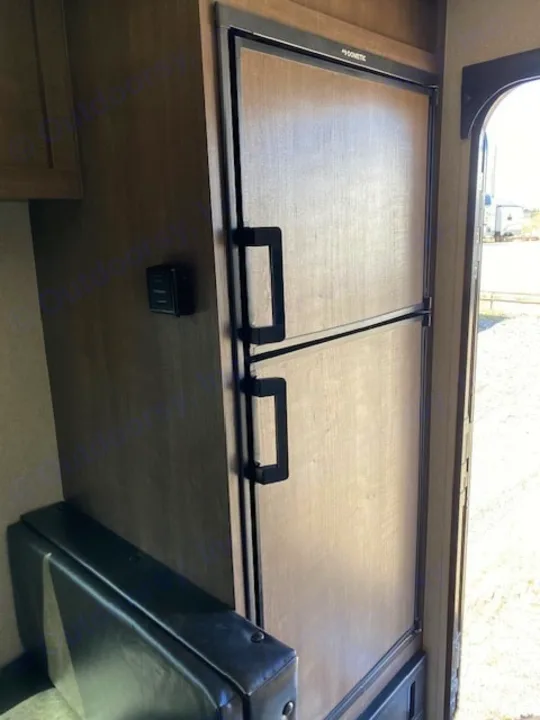 This RV rental interior features a Dometic two-door refrigerator, a wall-mounted thermostat, and a dark dinette bench.. Sunset Park RV Sun Lite 2021