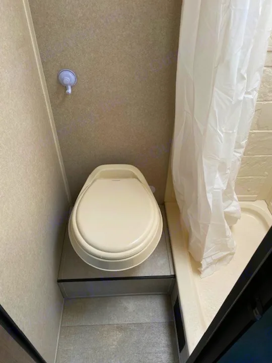 Inside an RV rental bathroom: compact design with a raised toilet, shower, and suction cup hook for convenience.. Sunset Park RV Sun Lite 2021
