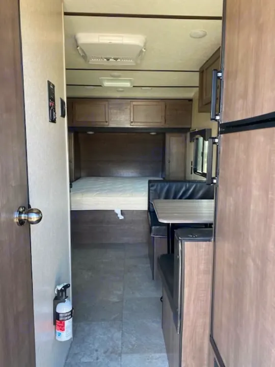 RV rental interior: A compact living space with a bed, dinette, refrigerator, and AC. Ideal for road trips.. Sunset Park RV Sun Lite 2021
