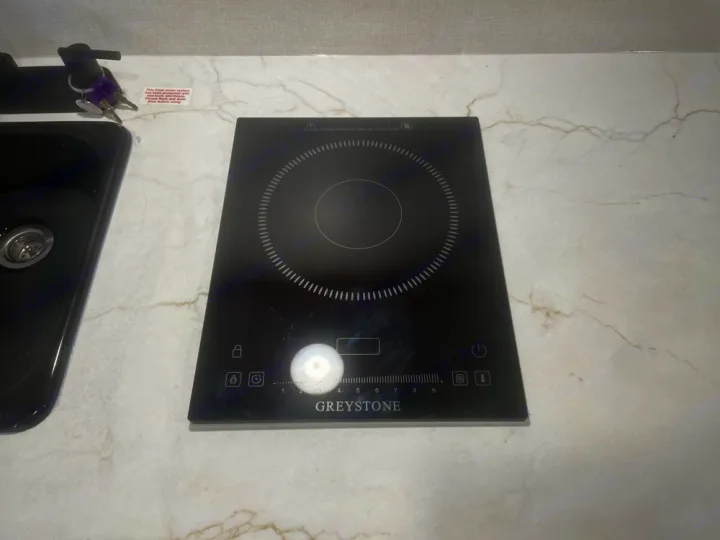 RV rental: A compact kitchen setup featuring a sleek black induction cooktop next to a sink. Ideal for travel cooking.. Keystone RV Coleman 13B 2025