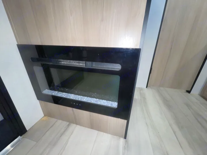 Modern electric fireplace in an RV rental, offering warmth and ambiance. Features sleek black glass & crystal media.. Keystone RV Coleman 13B 2025