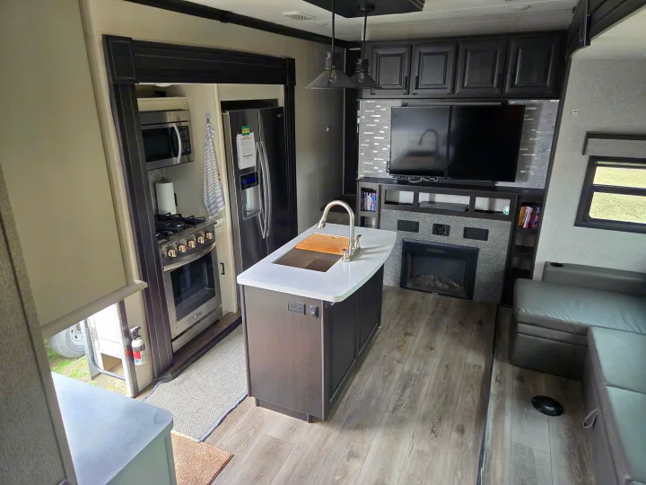Modern RV rental interior showcasing a full kitchen, island, living area with TV & fireplace, and comfortable seating.. Open Range Highland Ridge 2021