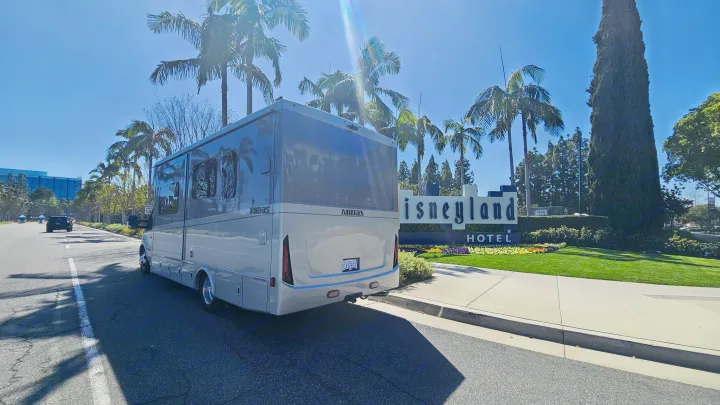 A sleek RV rental by Midas is parked at the iconic Disneyland Hotel entrance under sunny skies.. Tiffin Motorhomes Allegro Midas 24MT 2024