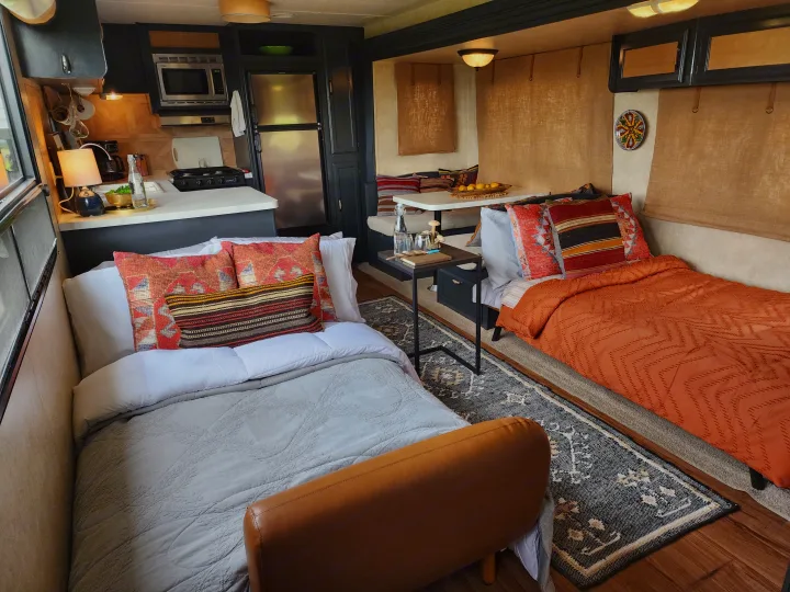 Warm RV rental interior with kitchen, dining, two beds, and inviting decor, offering a cozy travel experience.. Forest River Wildwood 2017