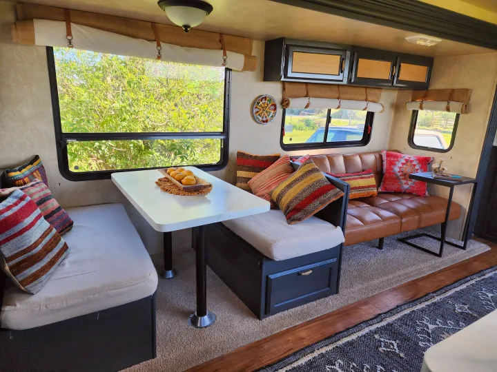 Spacious rv rental interior with a bright dining table, comfy sofa, and scenic window views.. Forest River Wildwood 2017