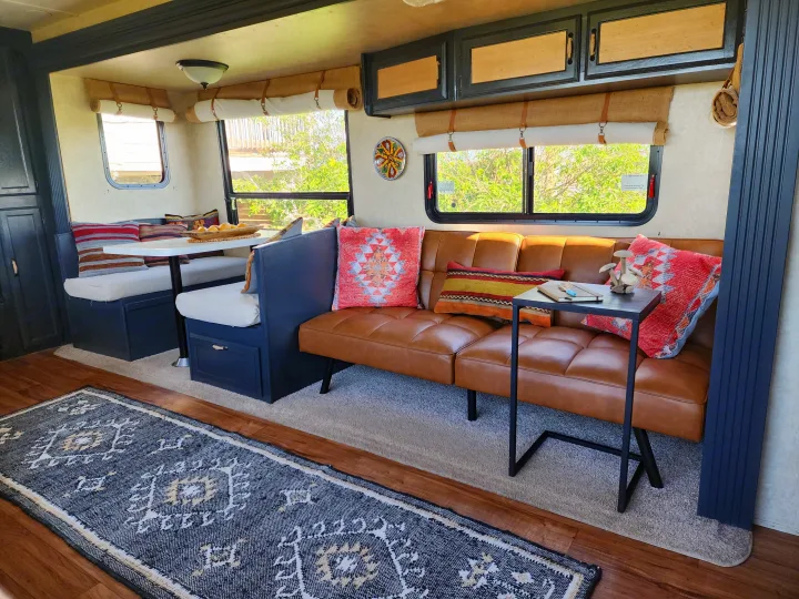 Inviting RV rental interior with a spacious dining booth, plush sofa, and natural light from the large windows.. Forest River Wildwood 2017