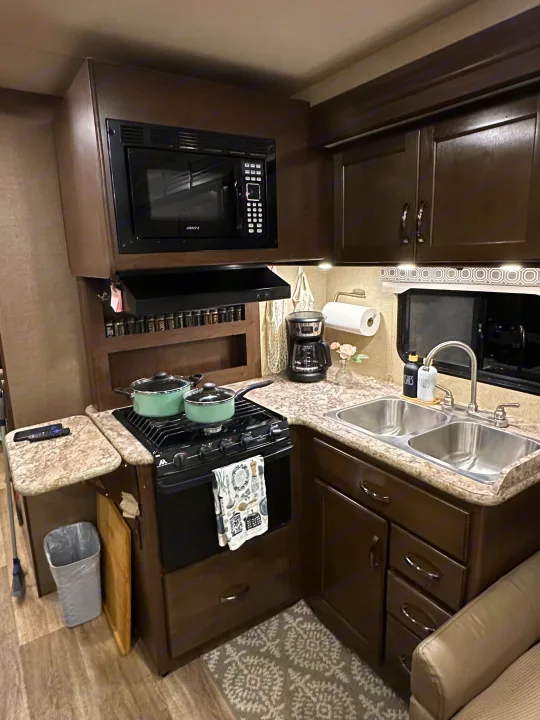 Experience convenient cooking in this RV rental kitchen, complete with a microwave, stove, double sink, and coffee machine.. Thor Four Winds 2018