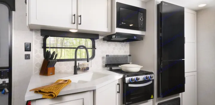 This RV rental offers a sleek, modern kitchen with white cabinets, a hexagon backsplash, black microwave, stove, and fridge.. Jayco Jay Flight 261BHS 2025