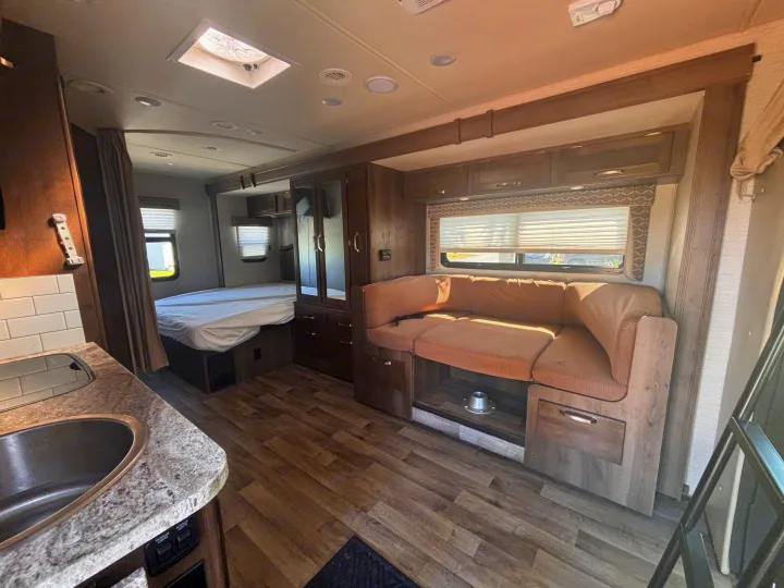 This RV rental interior offers a compact kitchen, private bed area, and comfortable dinette, ideal for travel.. Jayco Melbourne 2020