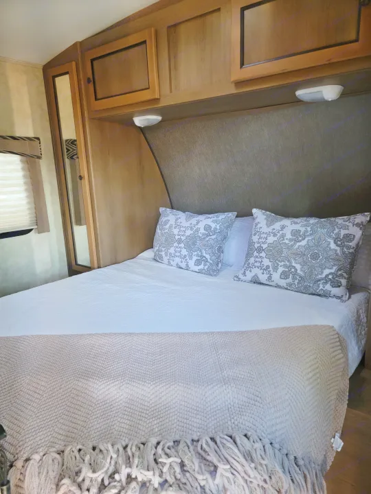 Cozy RV rental bedroom with patterned pillows, clean bedding, and practical overhead storage cabinets.. 5RXTD2221F1032421 Shadow Cruiser 2015