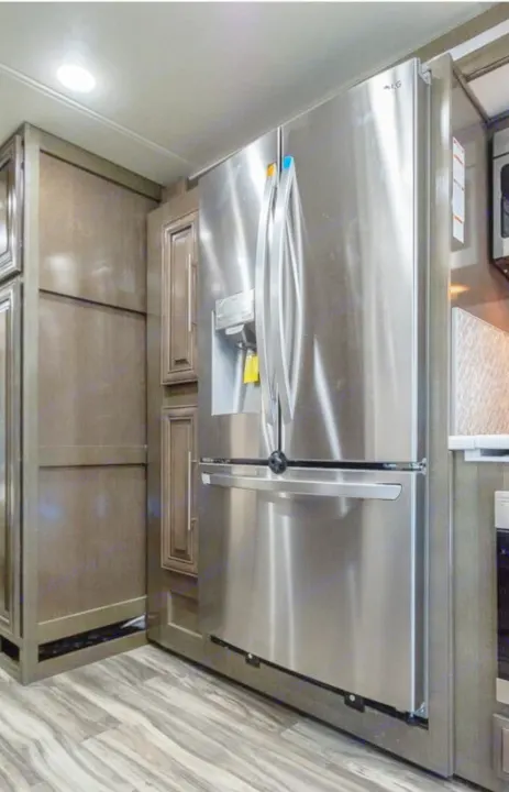 Modern RV rental kitchen featuring a stainless steel LG refrigerator, dark cabinetry, and wood-look flooring.. Georgetown GT7 2022