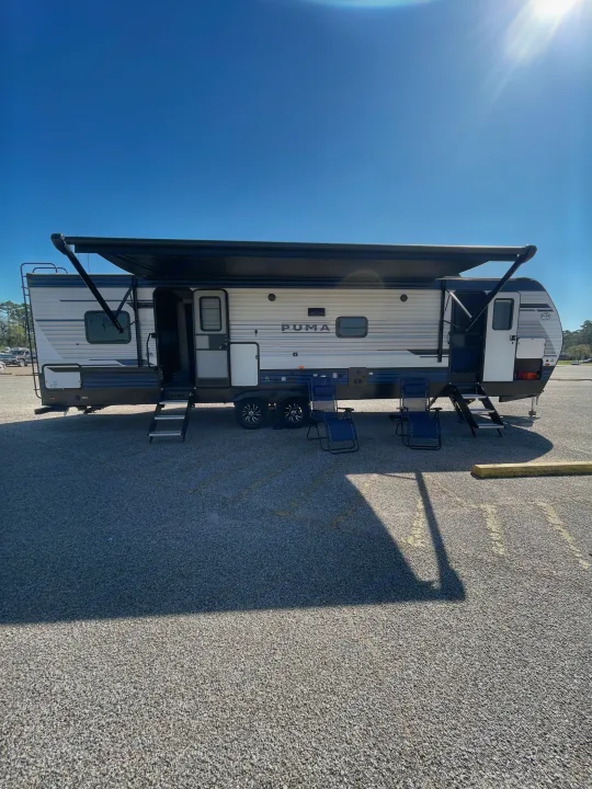 Spacious PUMA travel trailer RV rental with awning extended and chairs set up. Perfect for your next camping adventure.. Palomino Puma 337BH 2025