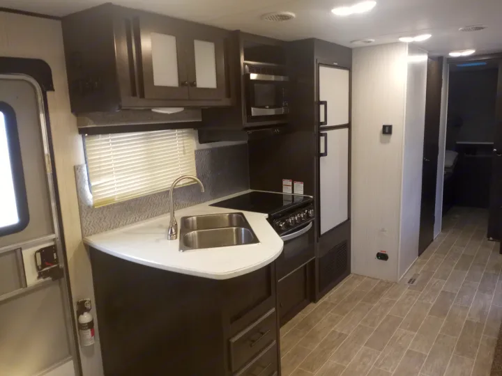 RV rental: modern kitchen with dark cabinets, white counters, stainless appliances, double sink, and light tiled floor.. Trail Runner heartland 25sle 2016
