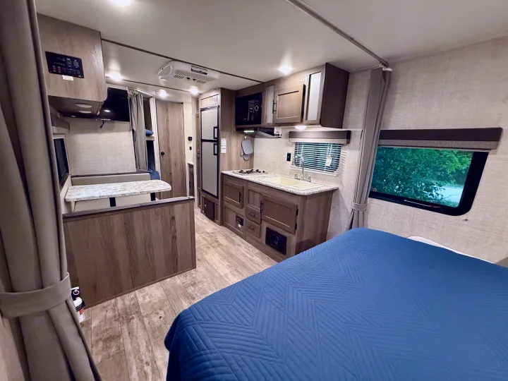 Inside a modern **rv rental**, featuring a full kitchen, comfortable bed, and dinette area, showing a functional layout.. Gulf Stream Kingsport 2021