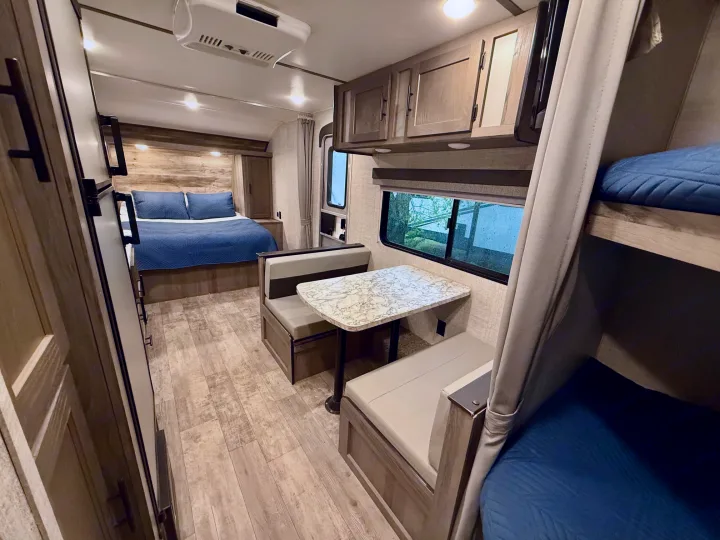 Comfortable RV rental interior: bedroom, dinette, and bunk beds visible. Ready for your next family adventure!. Gulf Stream Kingsport 2021
