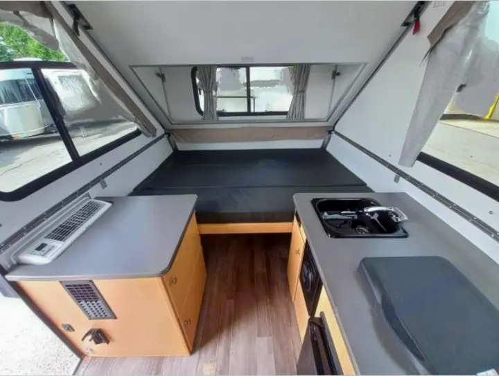 Compact RV rental interior featuring a bed, sink, and counter space, ideal for travel. Pop-up camper design shown.. A-Liner Ranger 2025