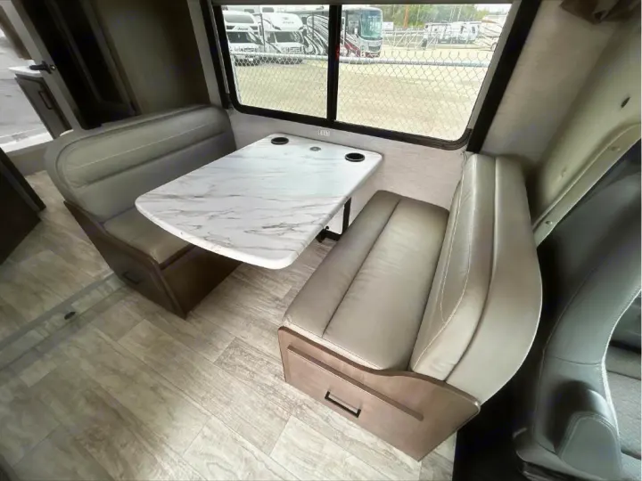 This spacious RV rental offers a comfortable dinette with a stylish faux marble table and light-toned upholstered benches.. GMC/THOR MAGNITUDE 2025
