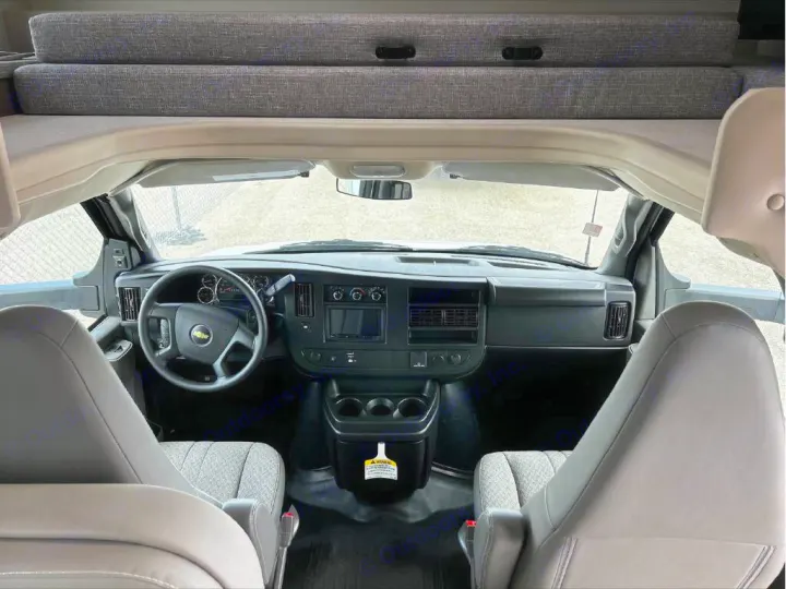 RV rental interior, from living area to the front cockpit, featuring steering wheel, dashboard, seats, and overhead bed.. GMC/THOR MAGNITUDE 2025