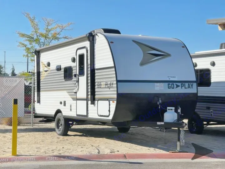Go Play white & gray travel trailer for RV rental, parked outside. Features include a black front, propane tank, & side awning.. Other Other 2025