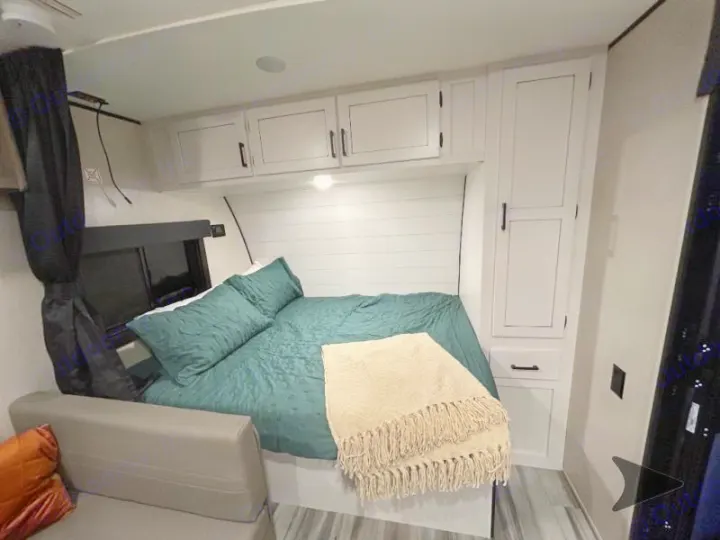 Comfortable RV rental bedroom featuring a green-covered bed, white cabinets, and a shiplap wall for your next trip.. Other Other 2025