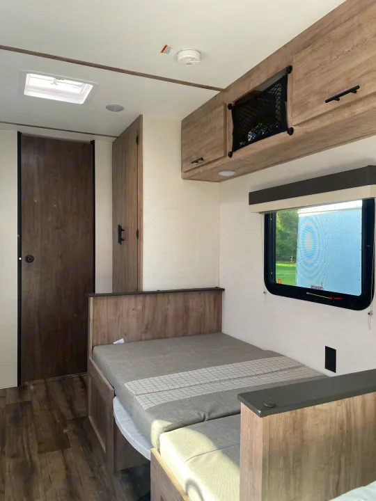 RV rental interior featuring a compact living space with a convertible bed/dinette, overhead storage, and a large window.. Gulf Stream Ameri-Lite 2024