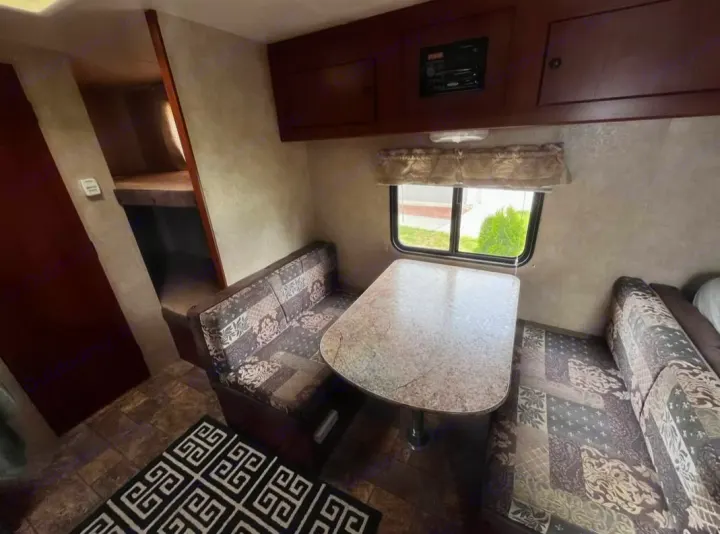 RV rental interior features a dinette with patterned benches, overhead cabinets, and bunk beds. Ideal for travel trailer living.. Forest River Salem Cruise Lite 2013
