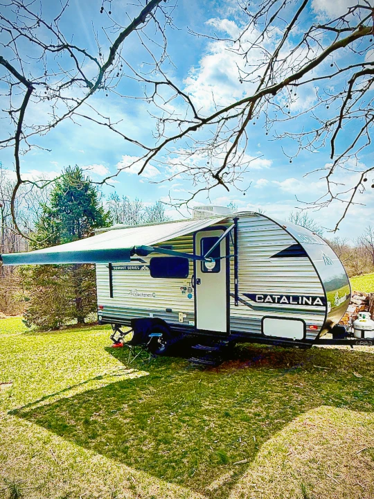 Coachmen Catalina Summit Series RV travel trailer with extended awning, ready for your rental outdoor adventure on grassy land.. Forest River Coachmen Catalina Summit 2024