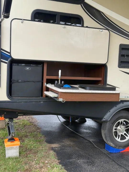 Explore this rv rental's exterior kitchen, featuring a sink, mini-fridge, and pull-out counter for outdoor cooking.. Keystone RV Bullet Ultra Lite 2017