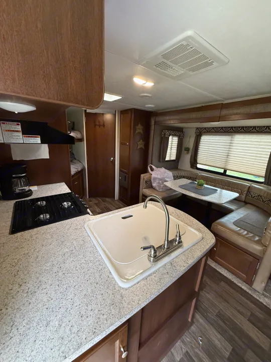 This RV rental's interior boasts a complete kitchenette with a sink & stove, a U-shaped dinette, and cozy bunk beds.. Keystone RV Bullet Ultra Lite 2017
