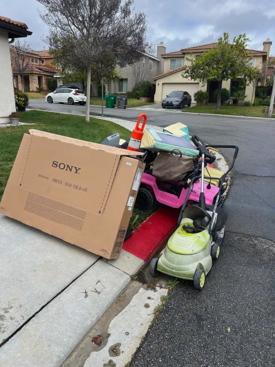 Residential street with bulky trash by the curb: Sony TV box, kids' ride-on, mower. No RV rental activity here.. SKY DMP 2024