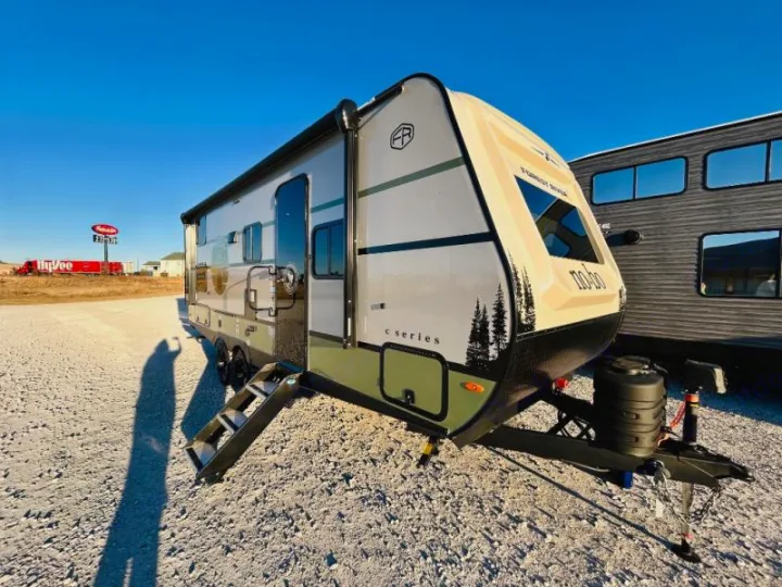 New Forest River No-Bo travel trailer, perfect for rv rental, on gravel. Bright sky, Hy-Vee sign visible.. Forest River No Boundaries NoBo 20.3 2025