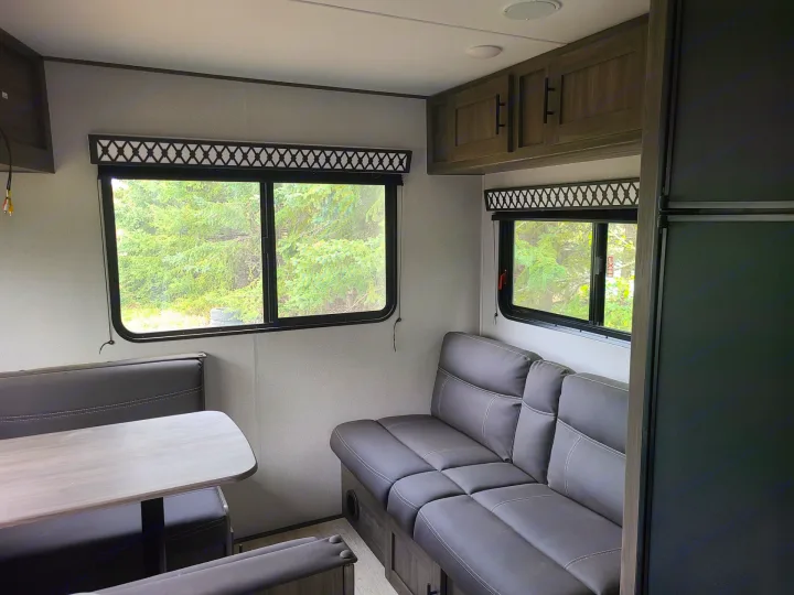 Explore this RV rental's cozy living space! Features a dinette, sofa, and large windows with natural light.. Forest River Shasta 2021